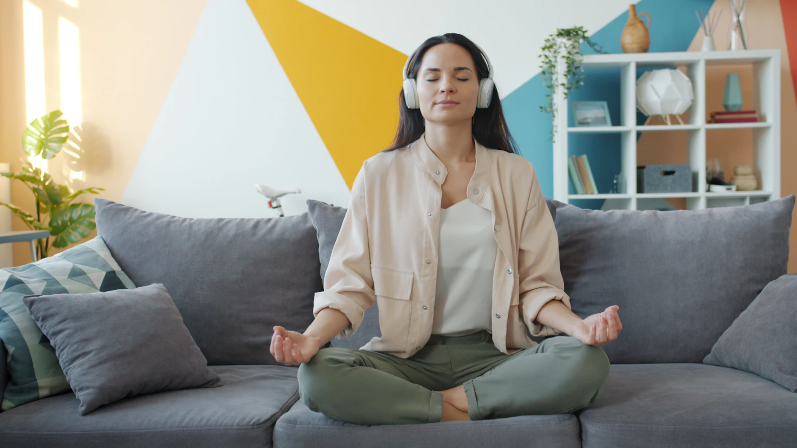 Woman meditating on a couch with headphones on