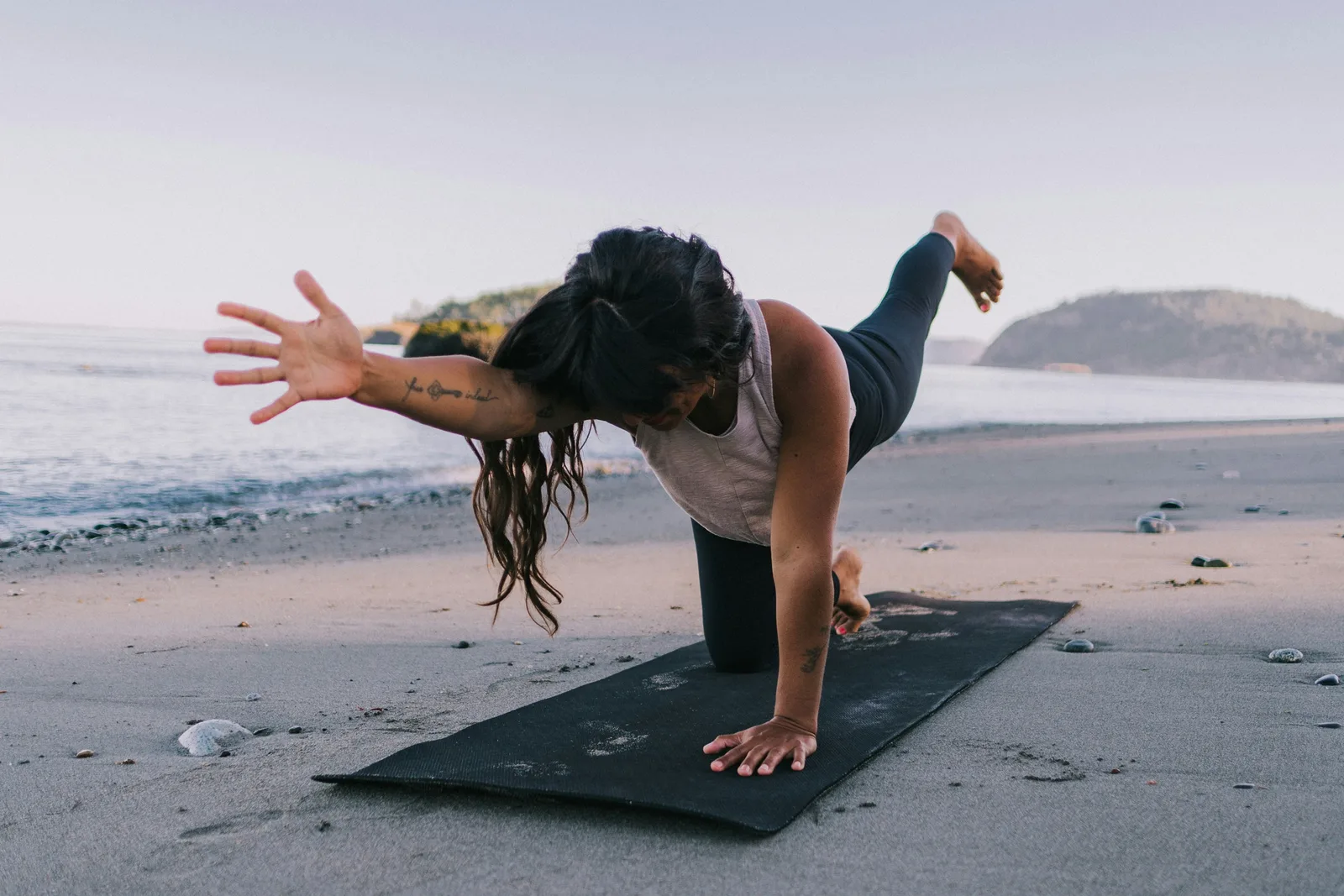 Person practicing yoga on a travel mat on the beach