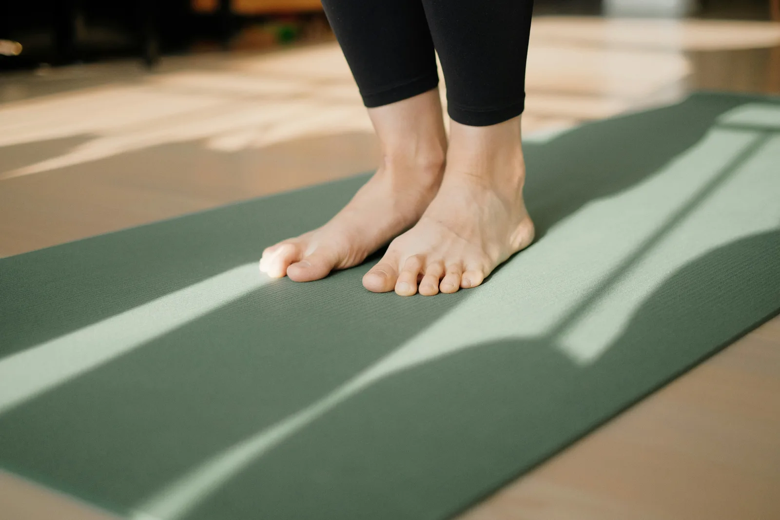 Persona de pie sobre una esterilla de yoga practicando en interior
