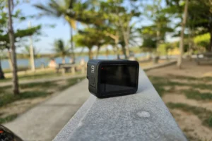 A small action camera on a concrete ledge with palm trees behind