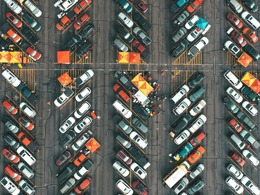 Aerial view of a large parking lot filled with rows of cars