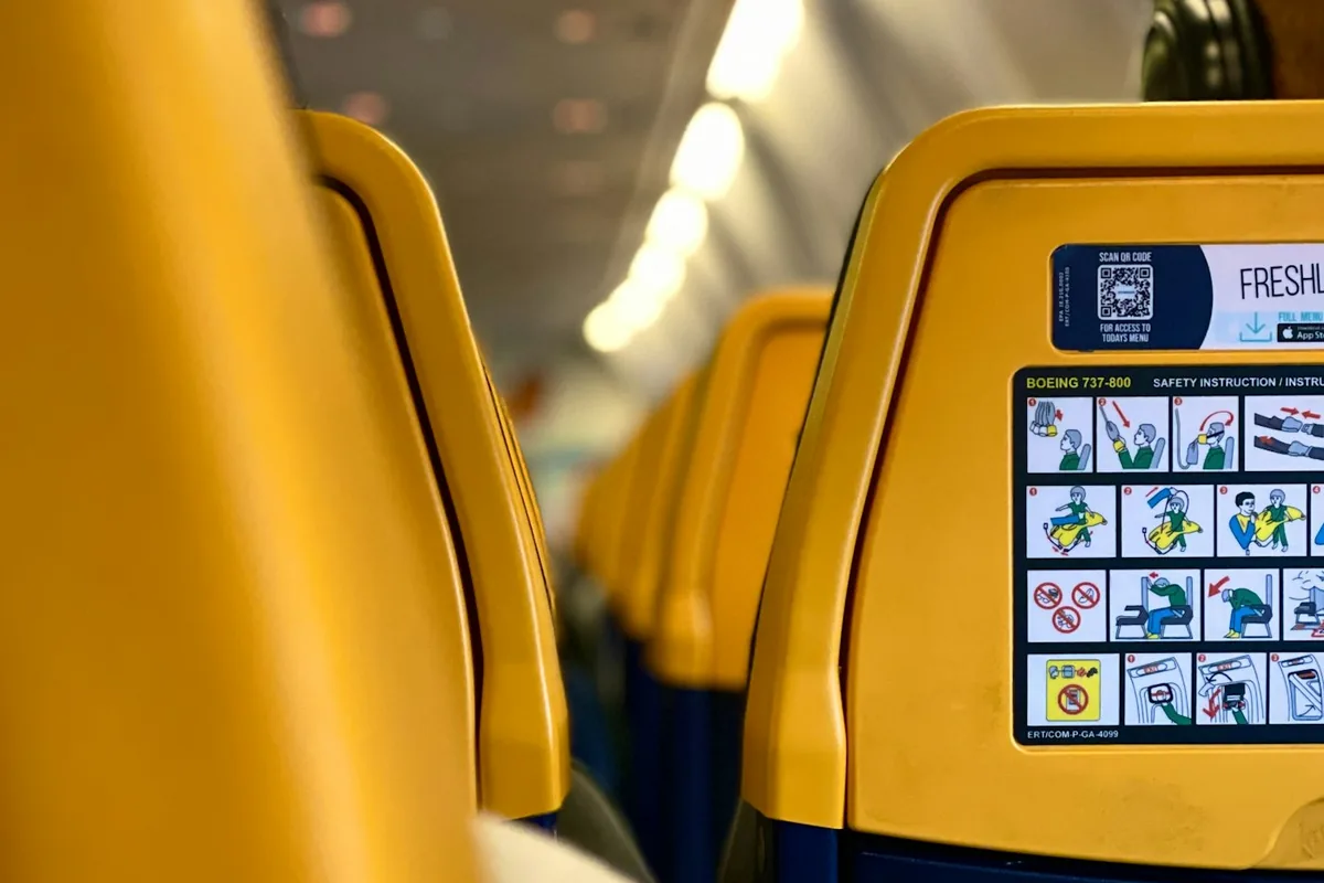 Gele en blauwe stoelleuningen langs het gangpad van een short-haul vliegtuigcabine
