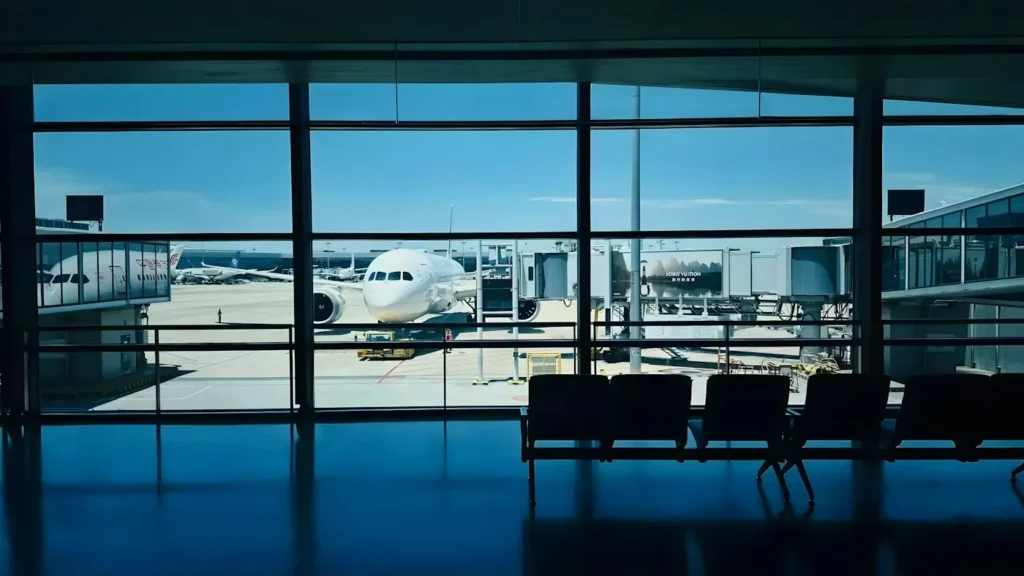 Airplane parked at a gate seen through the large window of an airport terminal
