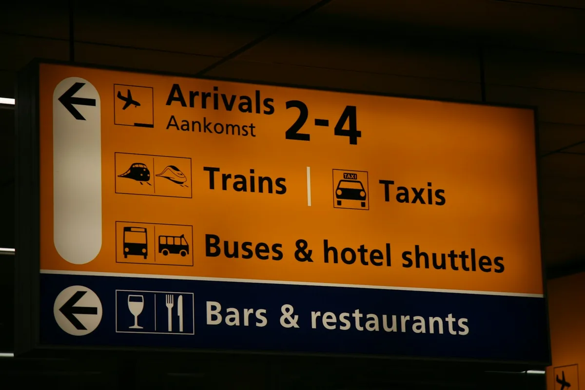 Airport arrivals sign pointing to trains, taxis, buses and hotel shuttles