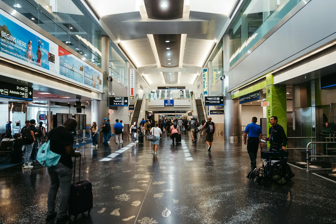 Travelers with suitcases walking through a busy airport hall
