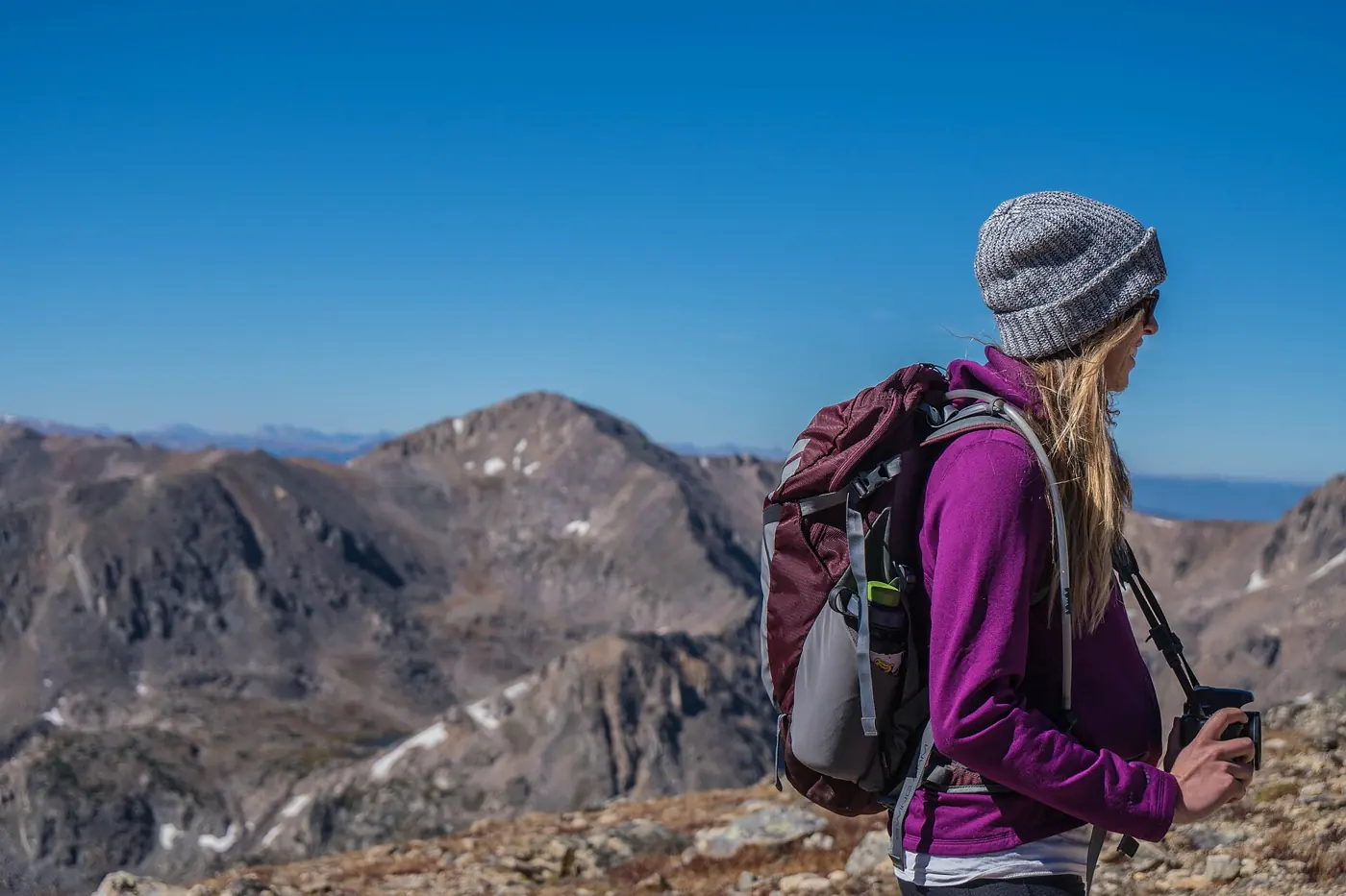 Backpacker mit Rucksack steht auf einem Bergkamm, leicht gepackt für einen Trip mit Actionkamera