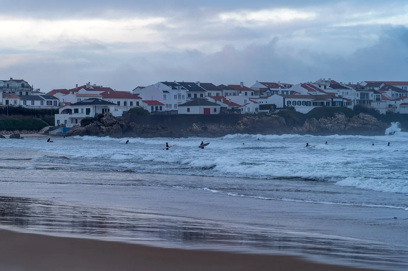 Surfers in the water in front of the white houses of Baleal near Peniche