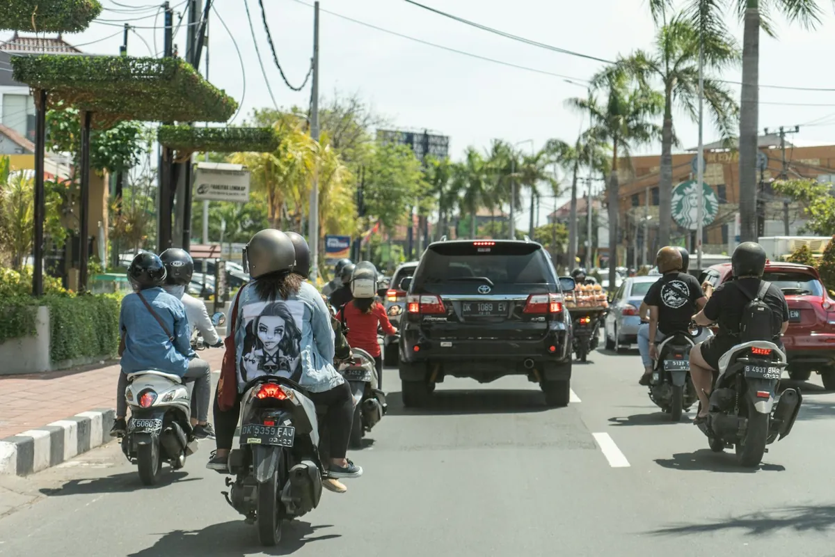Riders wearing helmets on scooters on a busy Bali road