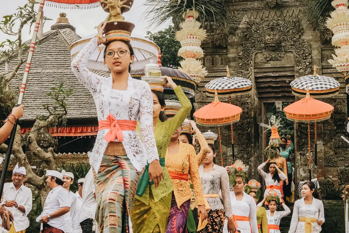 Mujeres con vestimenta tradicional llevando ofrendas en una ceremonia de templo en Bali