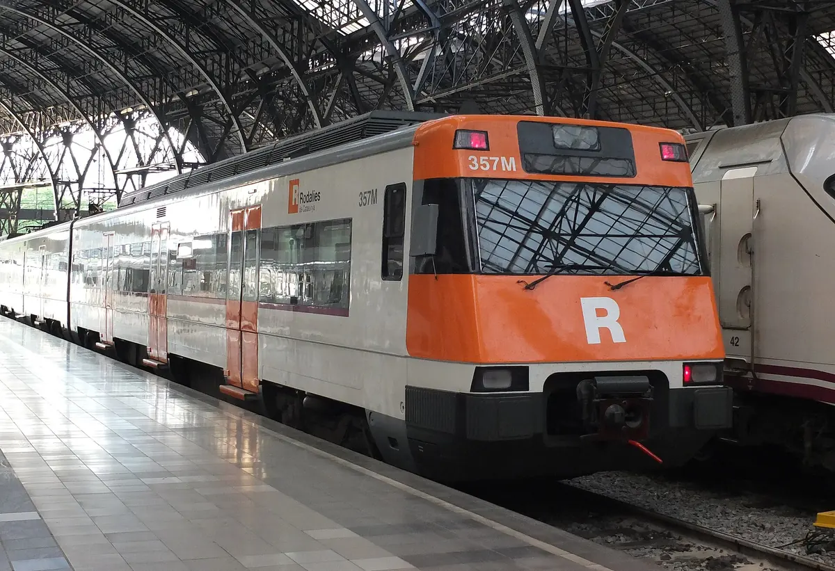 An orange and white Rodalies commuter train at a platform in Barcelona