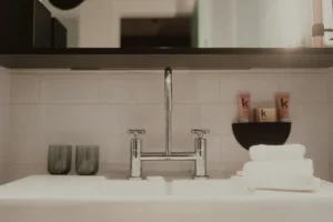 A bathroom sink with a chrome tap, two glasses and folded white towels
