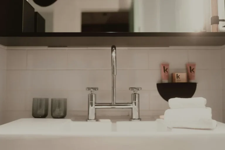 A bathroom sink with a chrome tap, two glasses and folded white towels