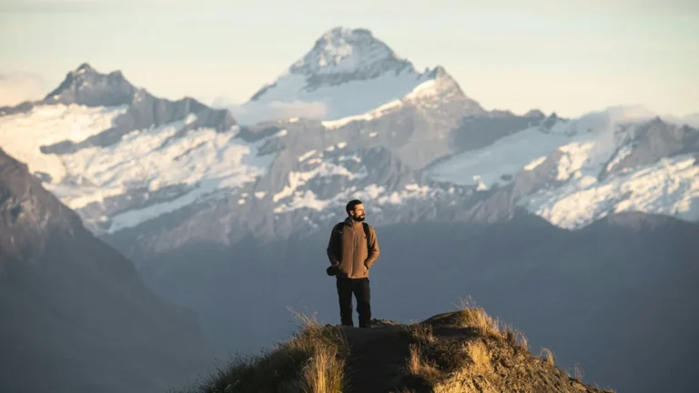 Traveler with a backpack on a mountain ridge, best travel insurance plans for digital nomads