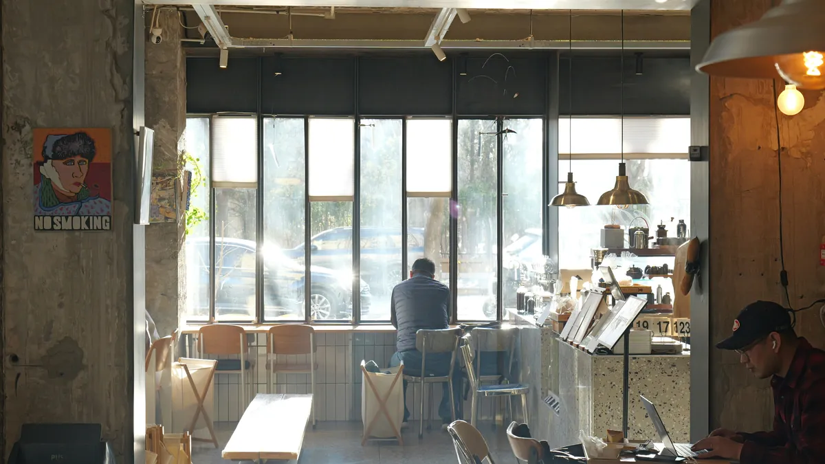 Remote workers on laptops in a sunlit cafe, best VPN for digital nomads on public wifi