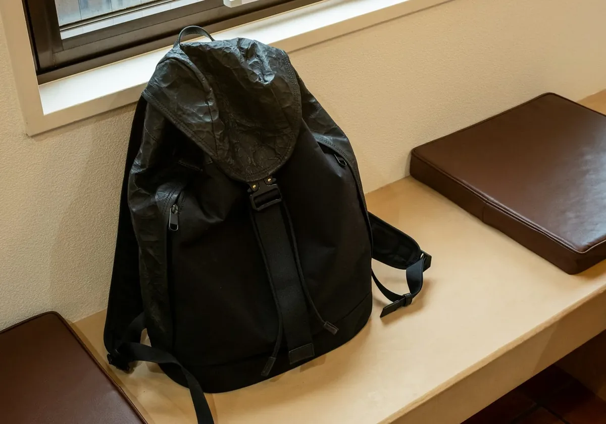 Black backpack resting on a bench next to a window
