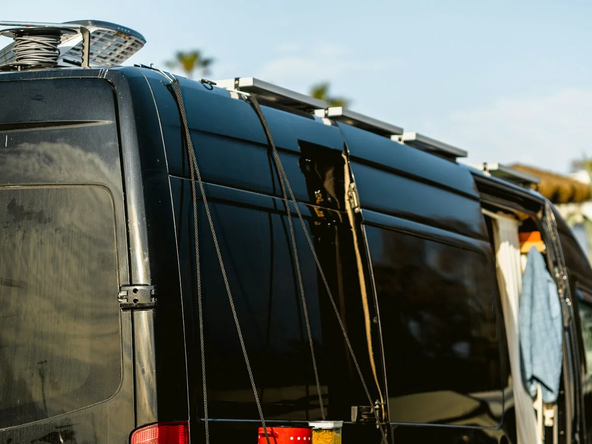 Rear of a black camper van with a roof rack