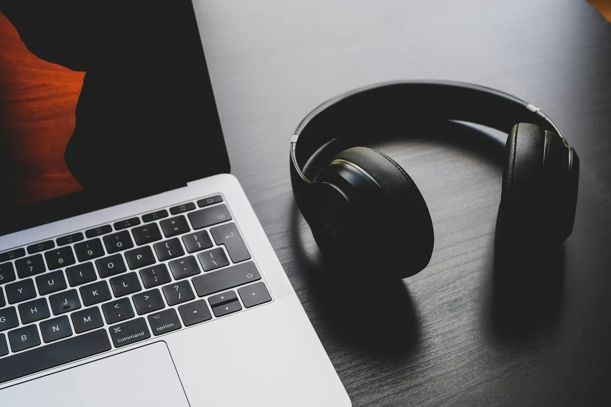 Black wireless headphones resting on a silver laptop keyboard