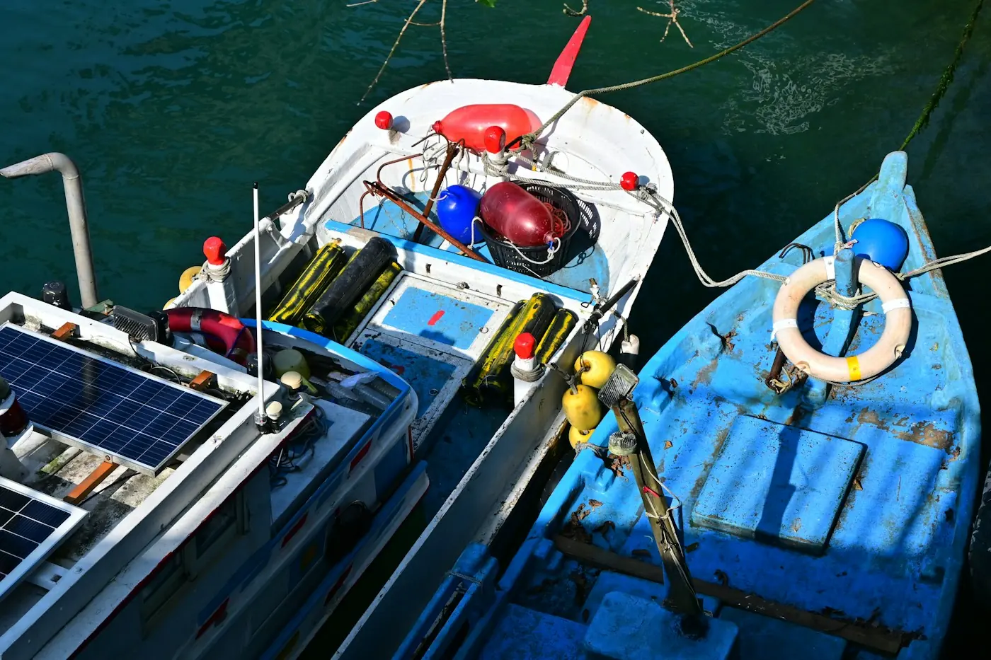 Boote liegen ruhig im Wasser, von oben gesehen, eines mit Solarpanels auf dem Deck