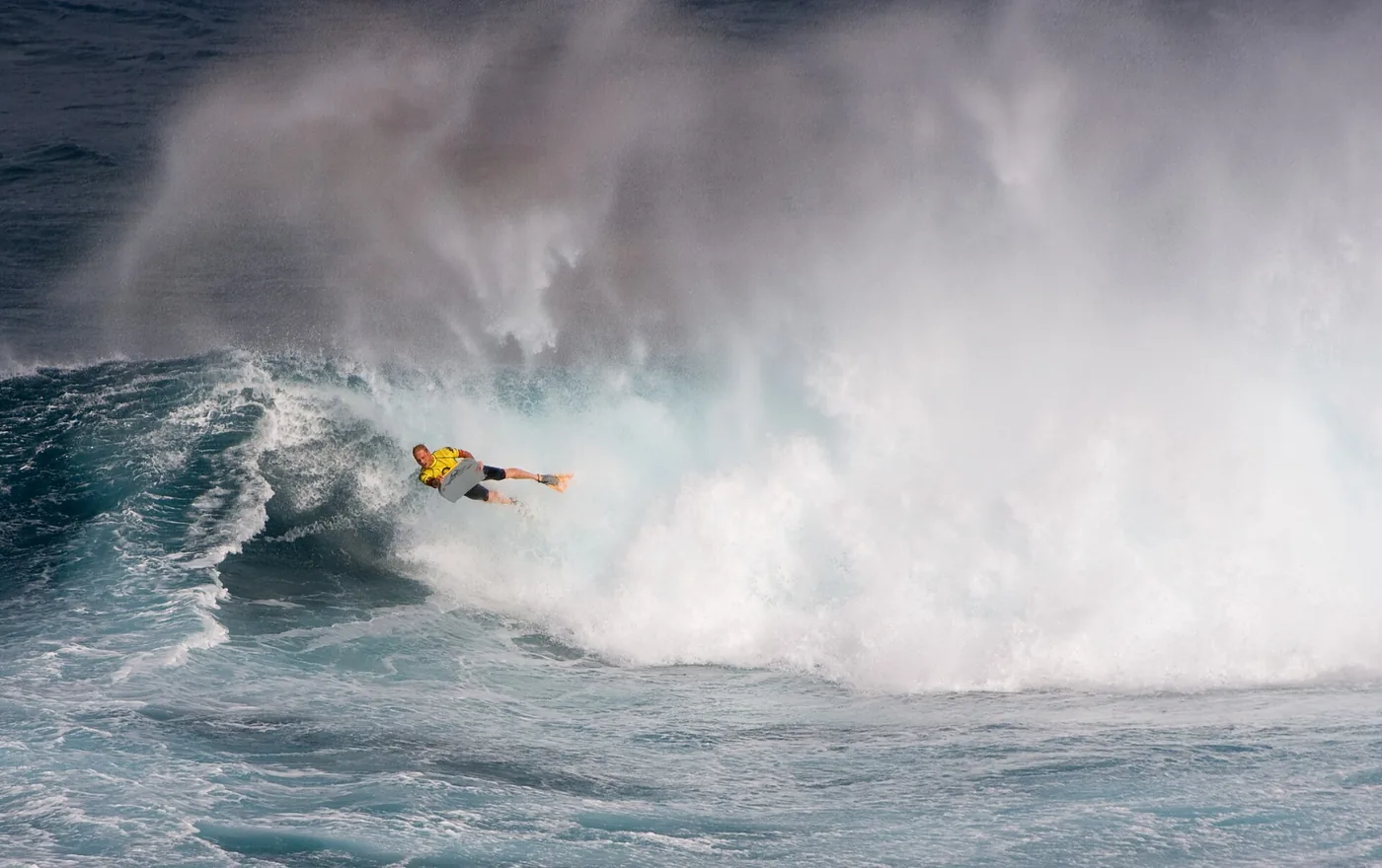 Huge wave exploding with spray at El Fronton in Gran Canaria with a bodyboarder in the air