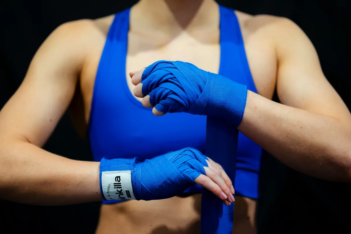 Boxer wrapping blue hand wraps around both hands, the small item that makes boxing while traveling easy to pack