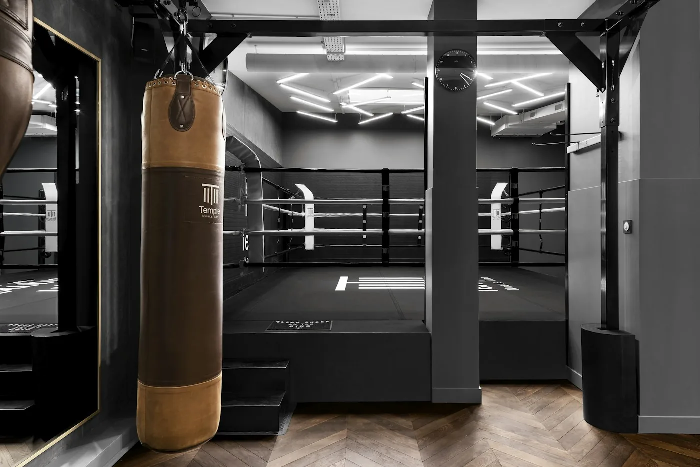 Boxing gym with a ring and a tall heavy bag in the foreground