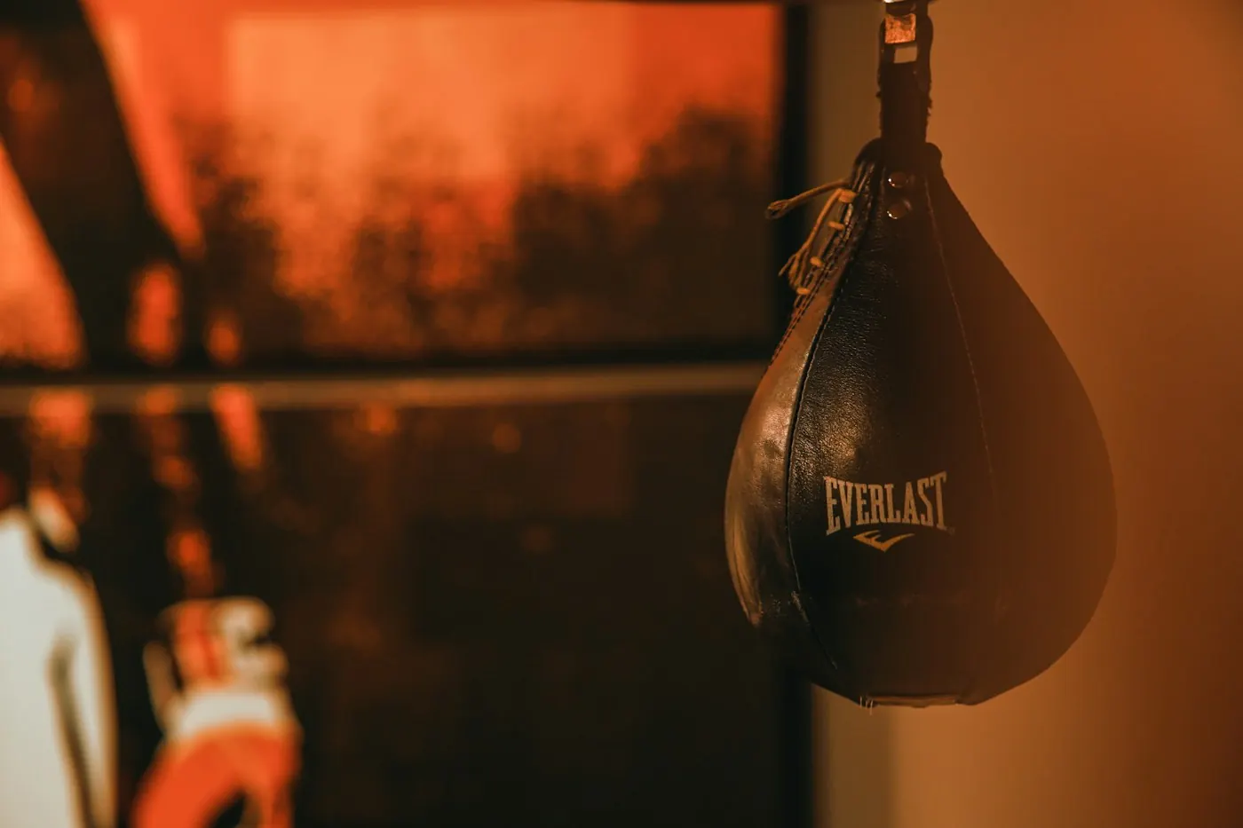 Leather speed bag hanging in a boxing gym in warm orange light