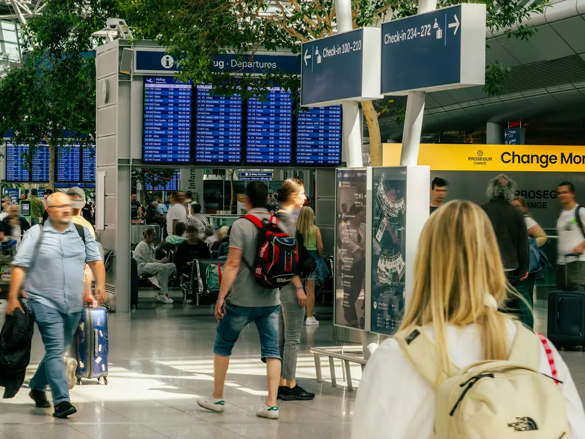 Busy airport terminal with departure boards and wayfinding signs