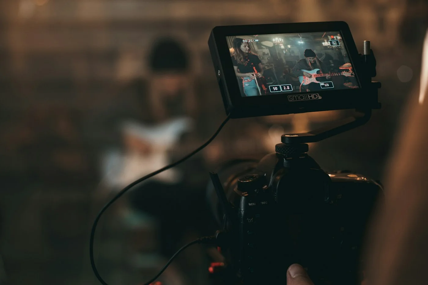 A camera monitor showing a musician with a guitar being filmed in a dark room
