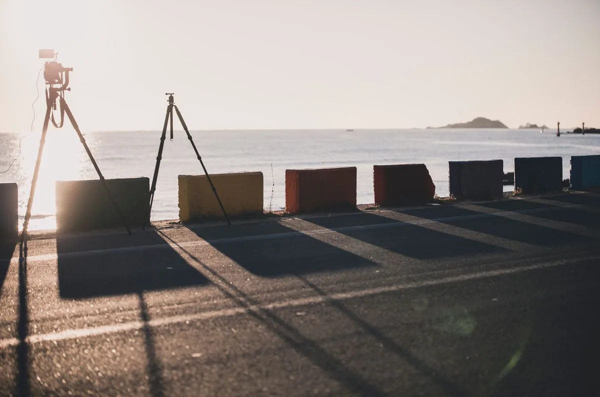 Two cameras on tripods on a seaside promenade at sunset