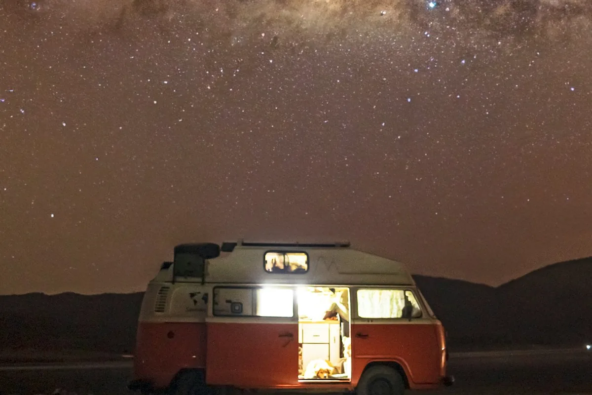 Camper van with the interior light on under a starry night sky