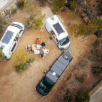 Camper mit Solarpanels auf dem Dach und einem losen Bodenpanel auf einem Campingplatz in der Wüste