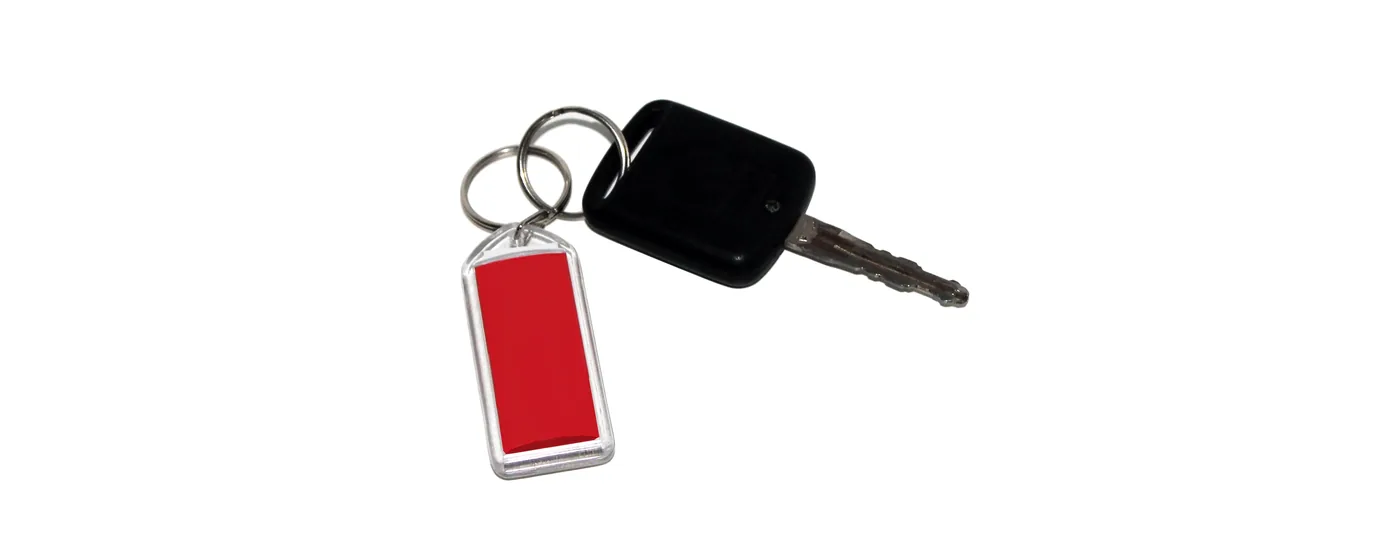 Llave de coche con cabezal de plástico negro y un llavero con una etiqueta roja sobre fondo blanco