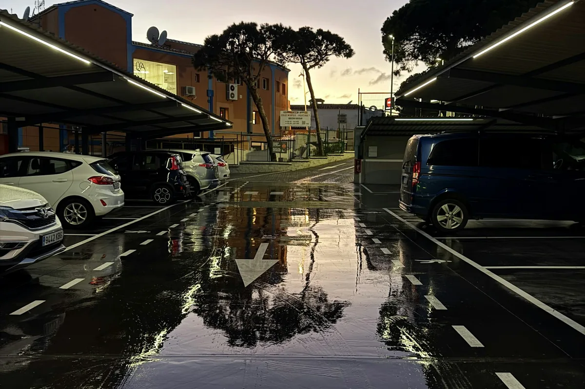 Car park at dusk with wet pavement reflecting the sky, car rental pickup checklist in Spain