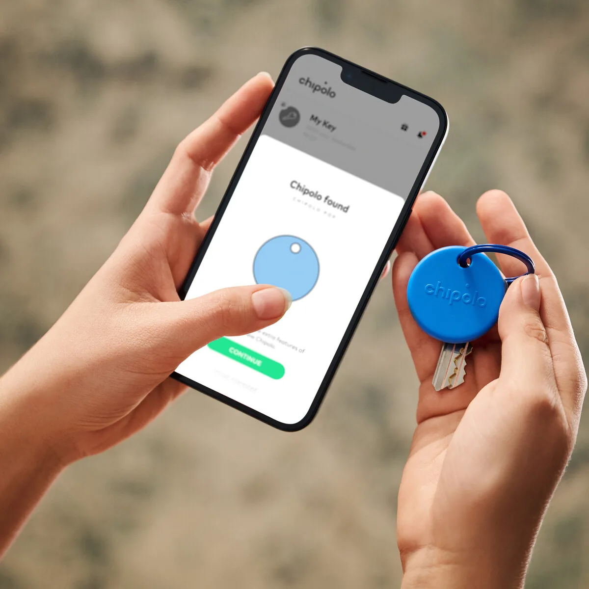 Hands holding a phone with the Chipolo app next to a blue Chipolo POP on a key ring