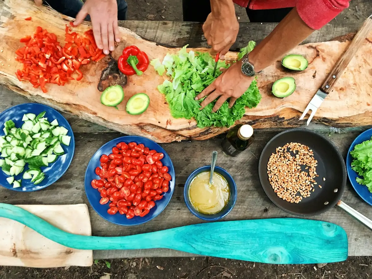 Hands chopping fresh vegetables and herbs on a wooden board