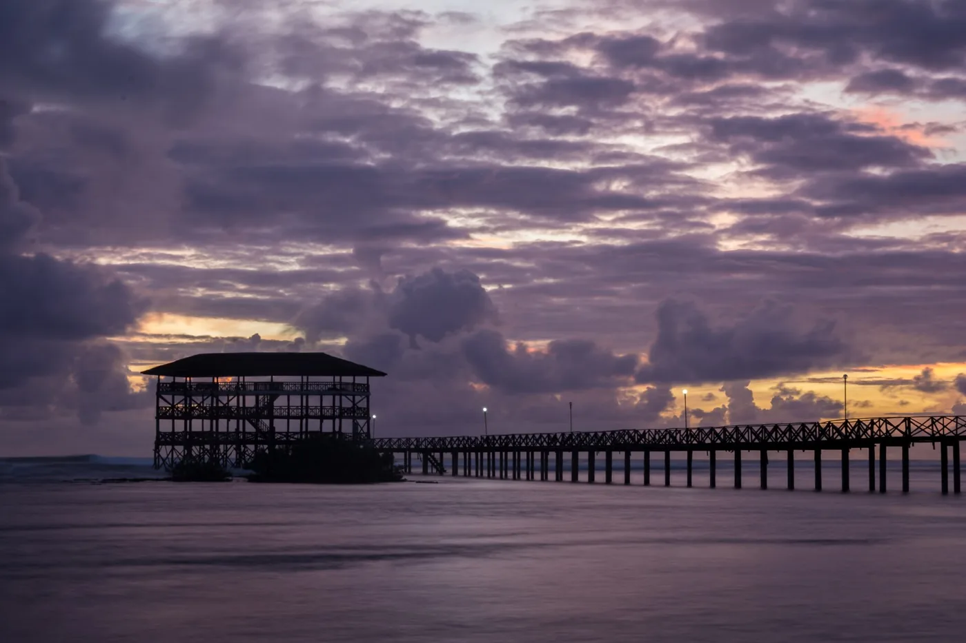 The Cloud 9 boardwalk and tower on Siargao at dusk under purple clouds
