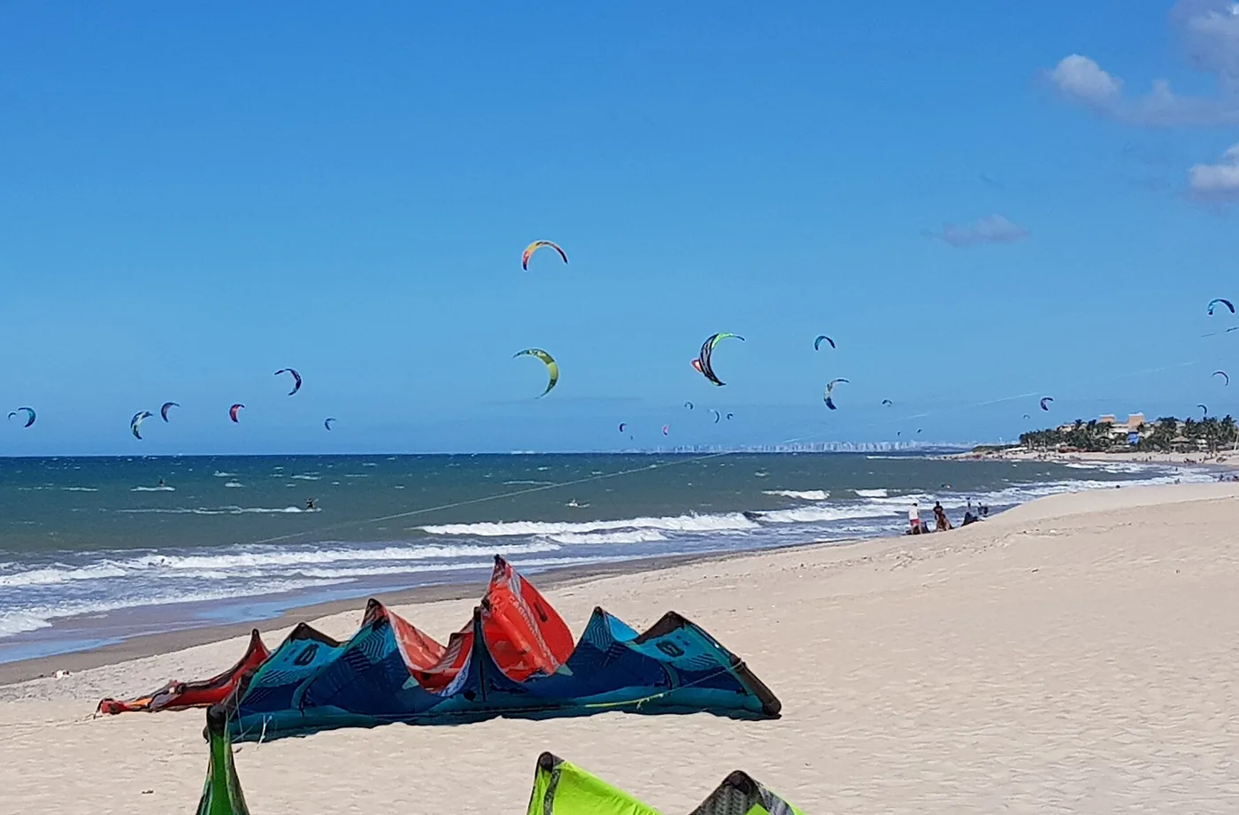 Kitesurfers on the water off Cumbuco beach in Ceara, Brazil, with kites laid on the sand