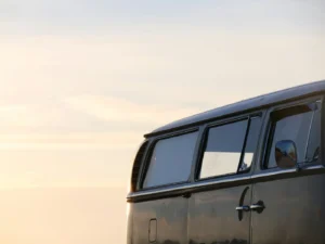 Dark gray vintage camper bus with tinted side windows in evening light