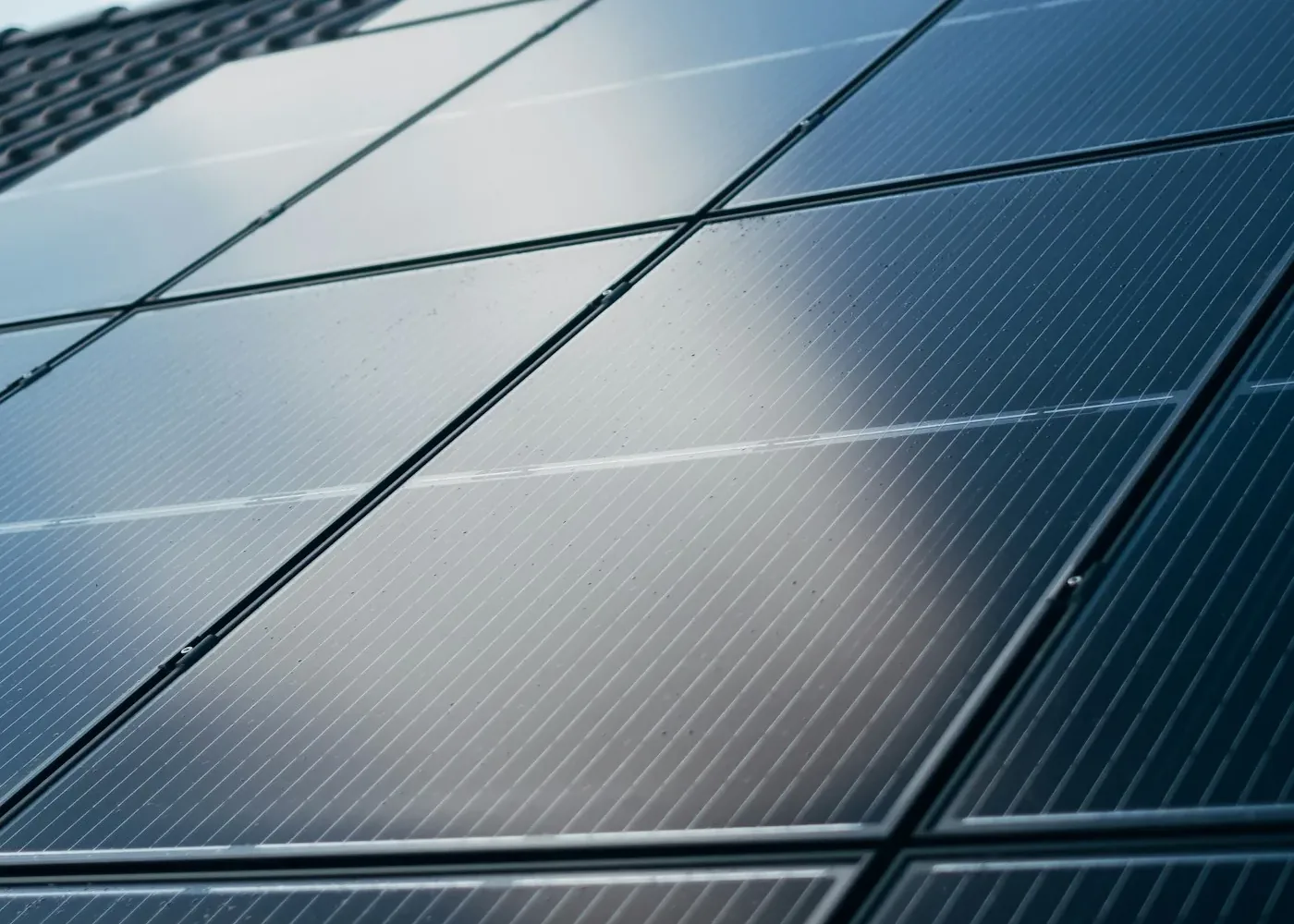 Close-up of a dark blue solar panel with glass reflecting the sky