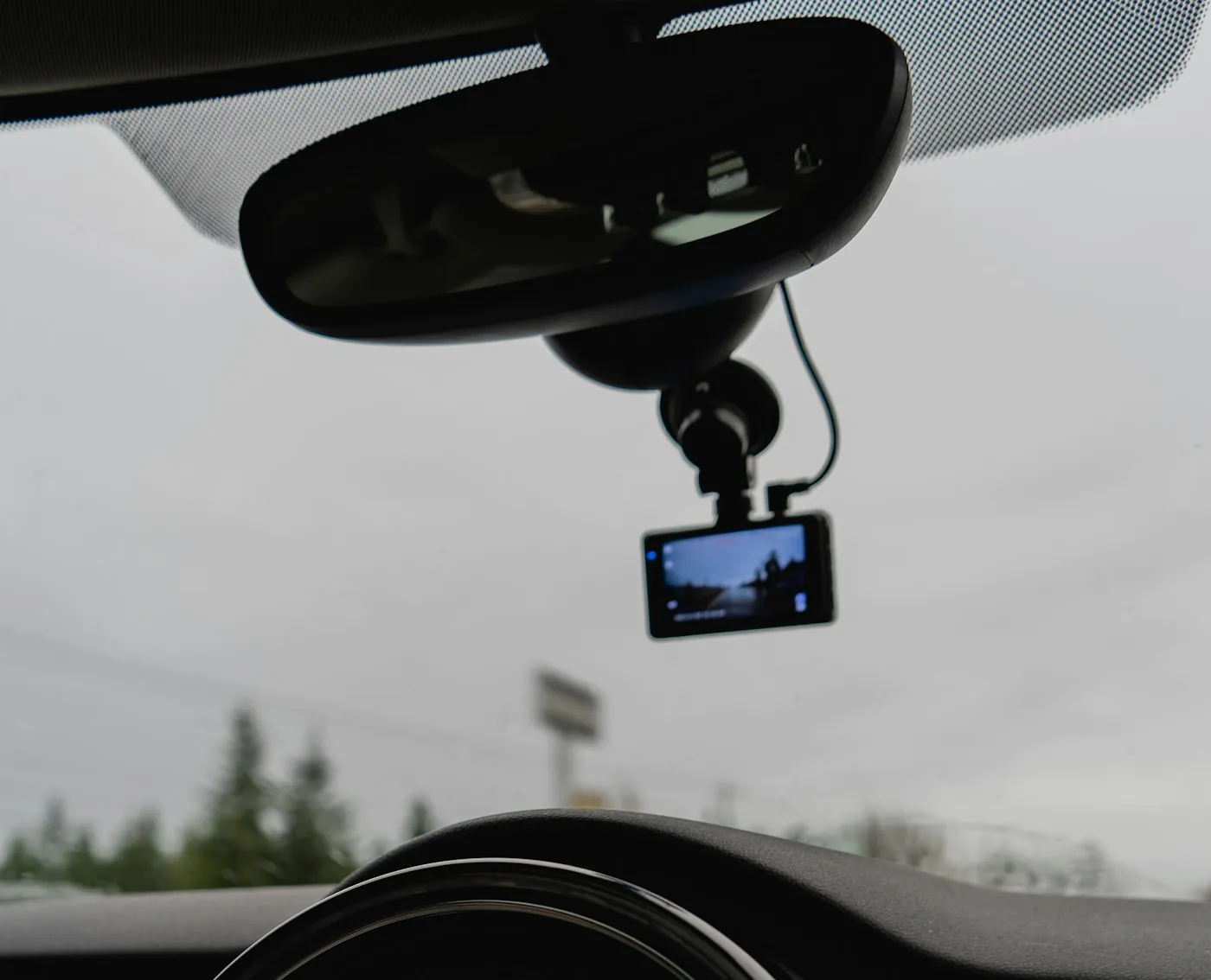 Dashcam, die unter dem Rückspiegel hängt, mit einem runden Navigationsbildschirm auf dem Armaturenbrett