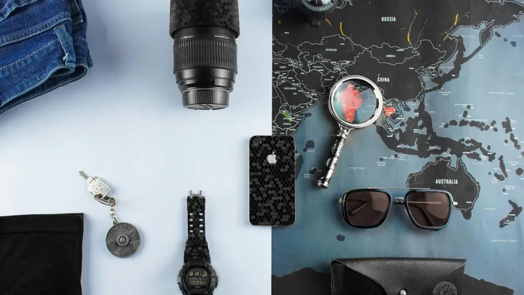 Camera lens, phone, watch and sunglasses on a world map, digital nomad packing list