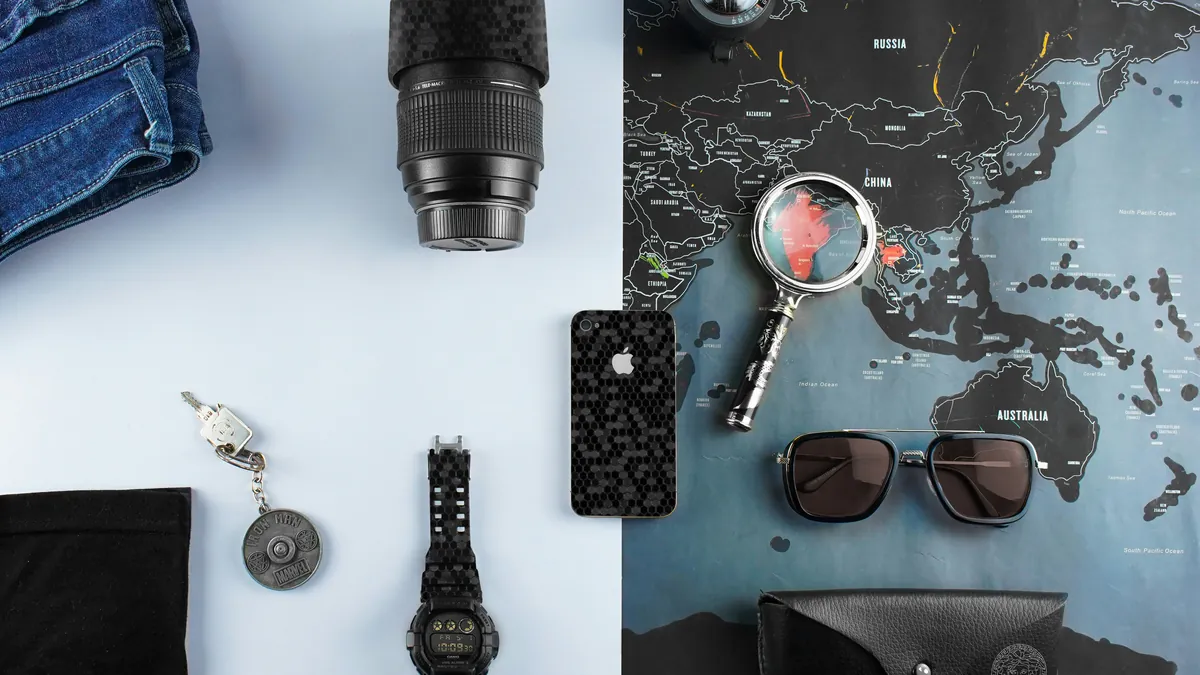 Camera lens, phone, watch and sunglasses on a world map, digital nomad packing list