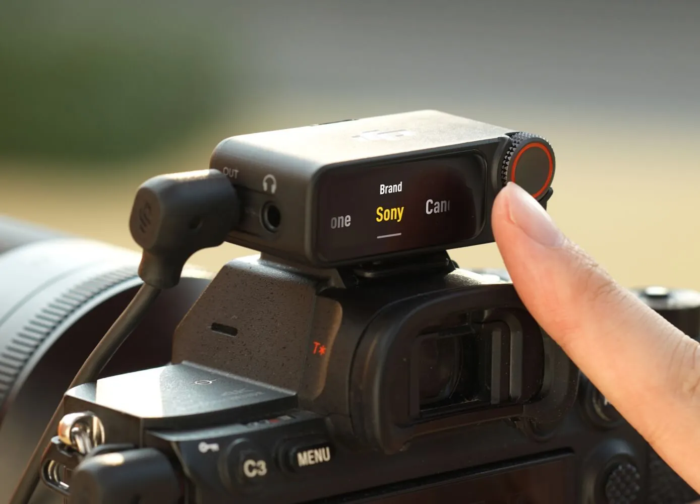 DJI Mic 2 receiver on a mirrorless camera hot shoe with a finger turning its dial