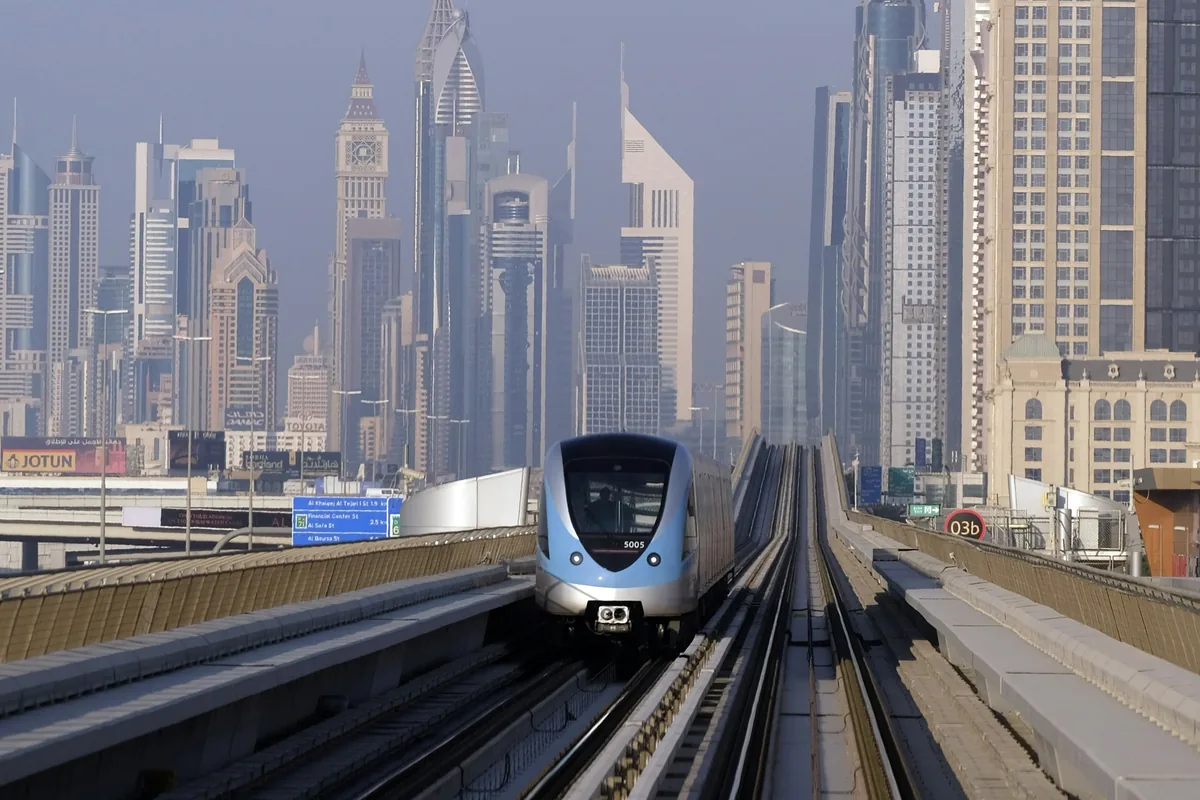 Tren del Metro de Dubái circulando entre rascacielos junto al horizonte de la ciudad