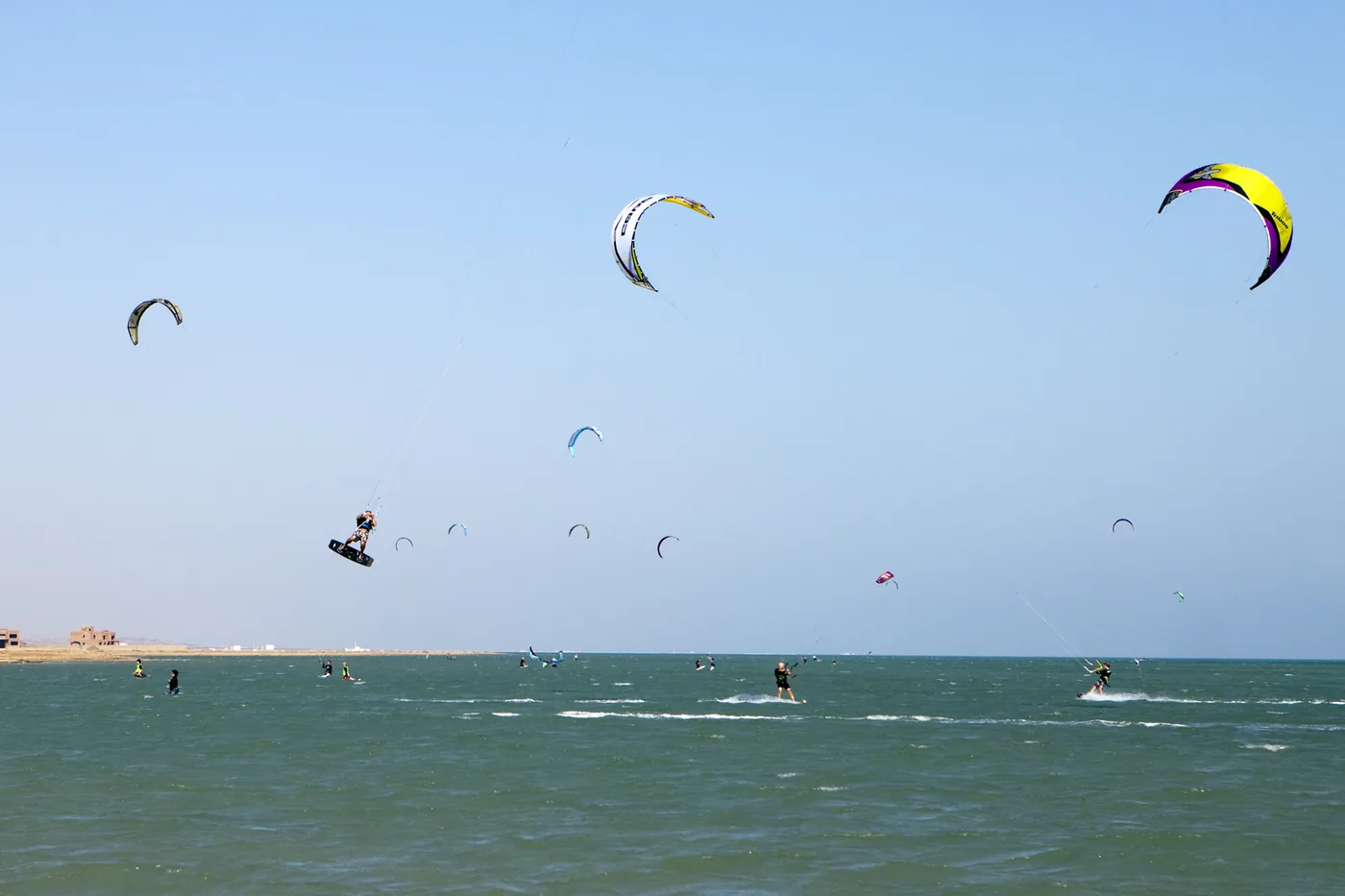 Kitesurfers and kites in a blue sky over the lagoon at El Gouna