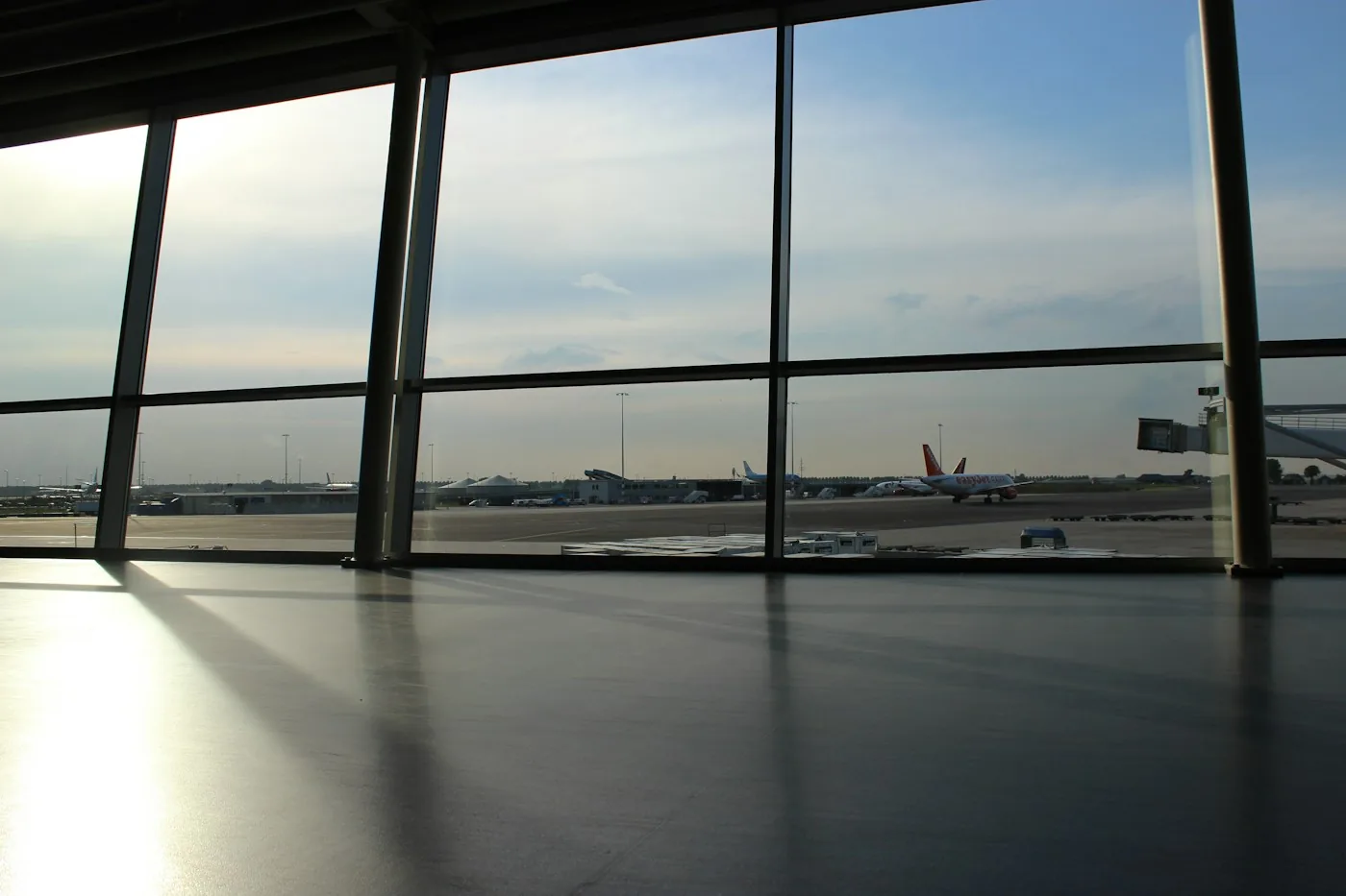 Empty airport terminal with large windows and long shadows on the floor