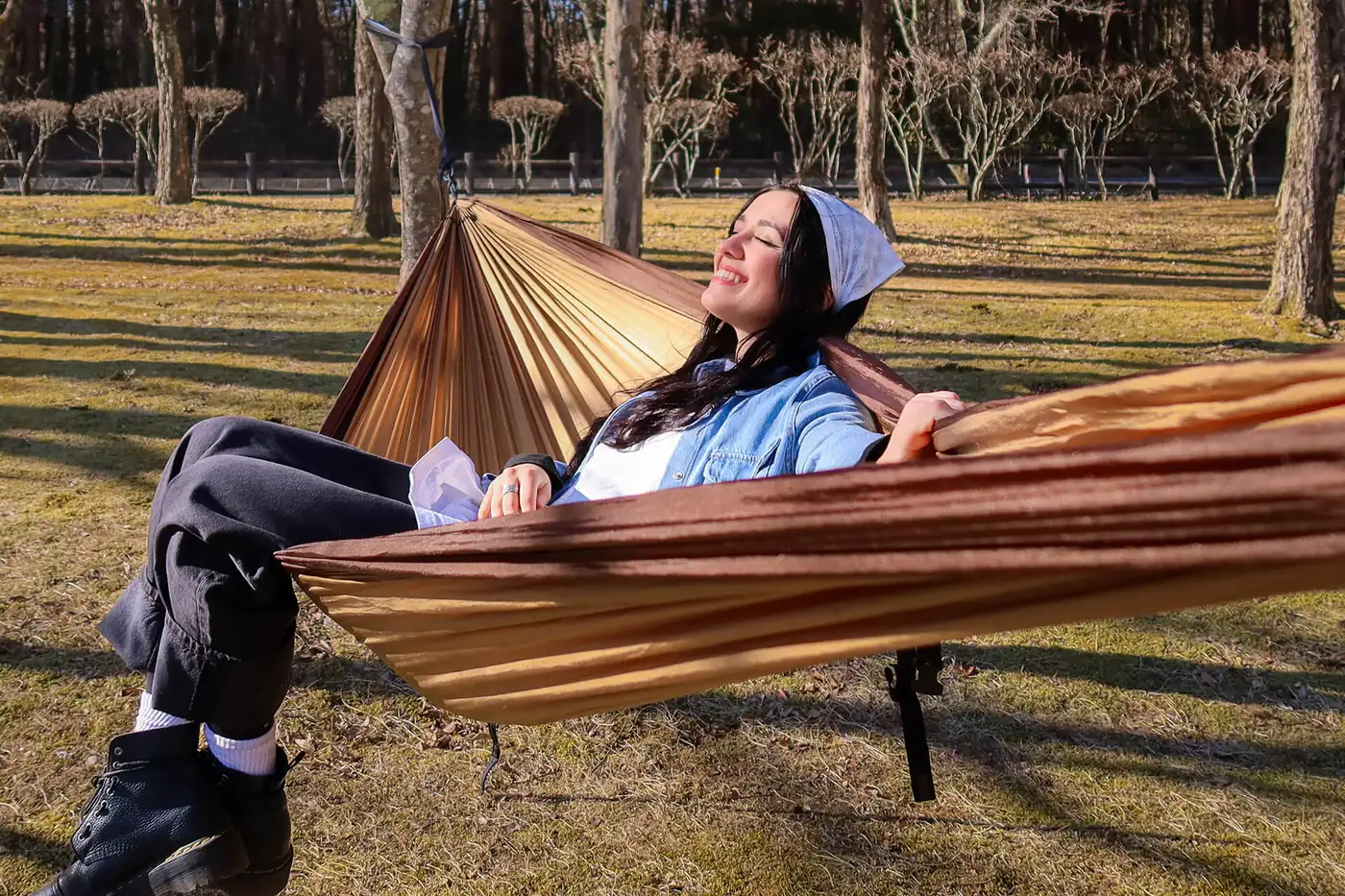 Woman smiling in an ENO DoubleNest hammock in a park