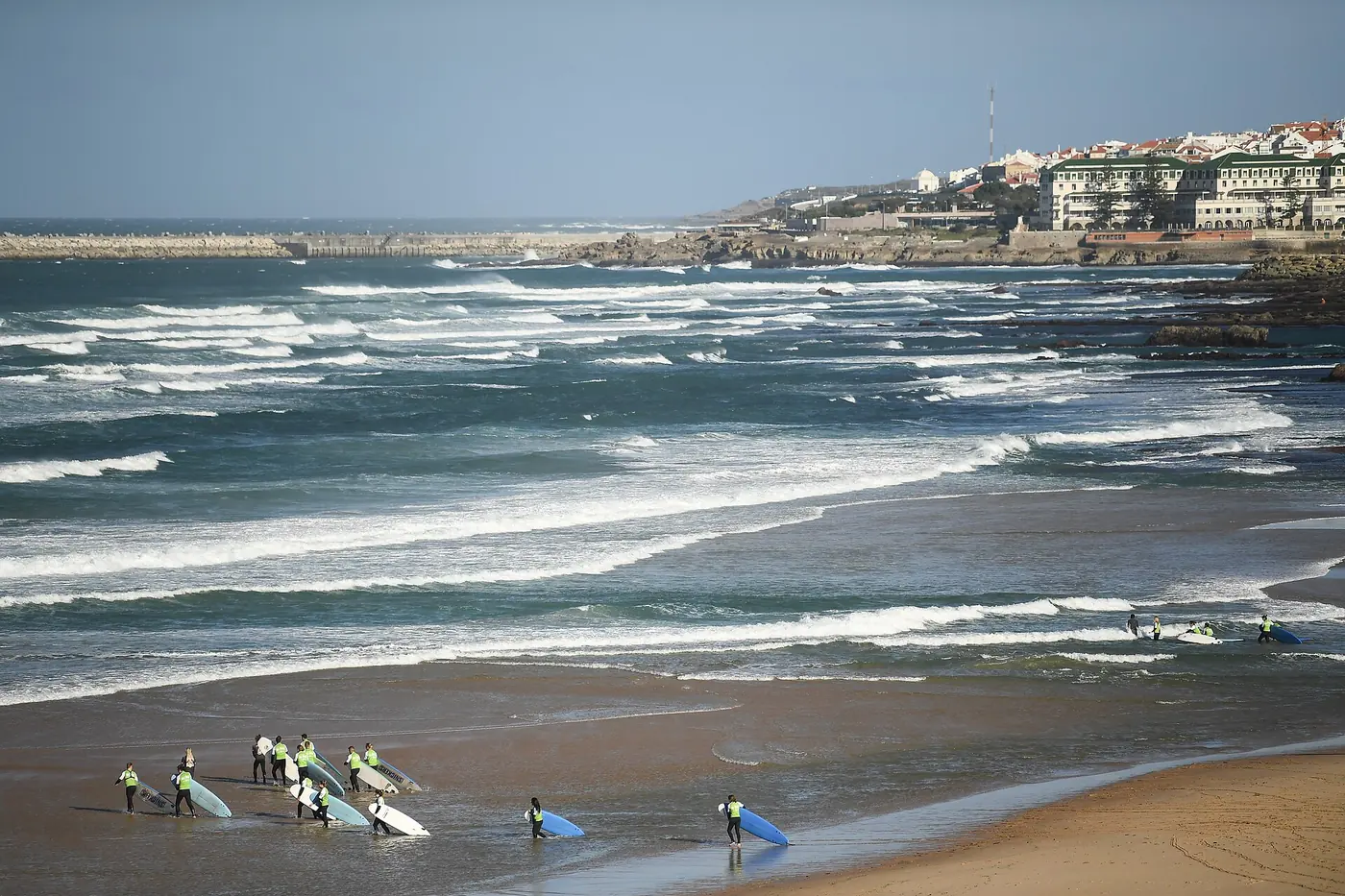 Waves rolling onto Foz do Lizandro beach in Ericeira with surf students on the sand