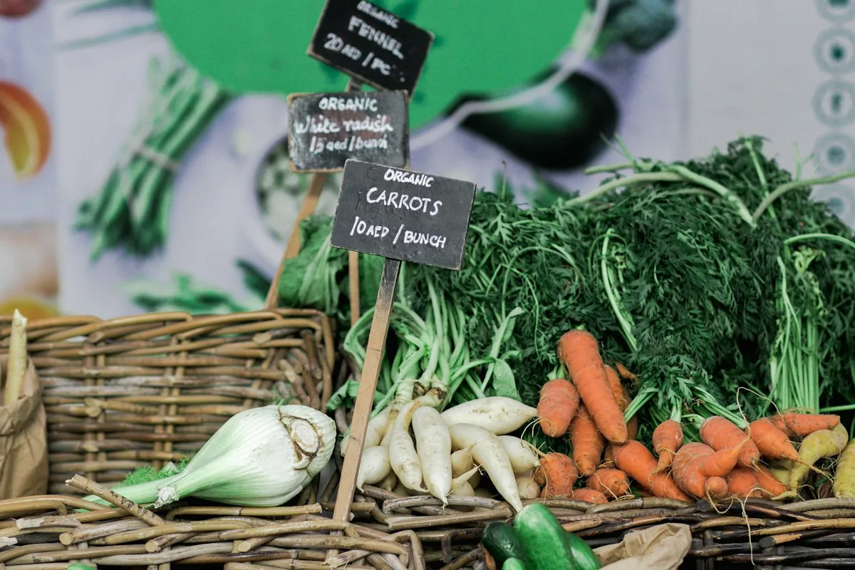 Baskets of carrots, radishes and leafy greens at a vegetable market stall