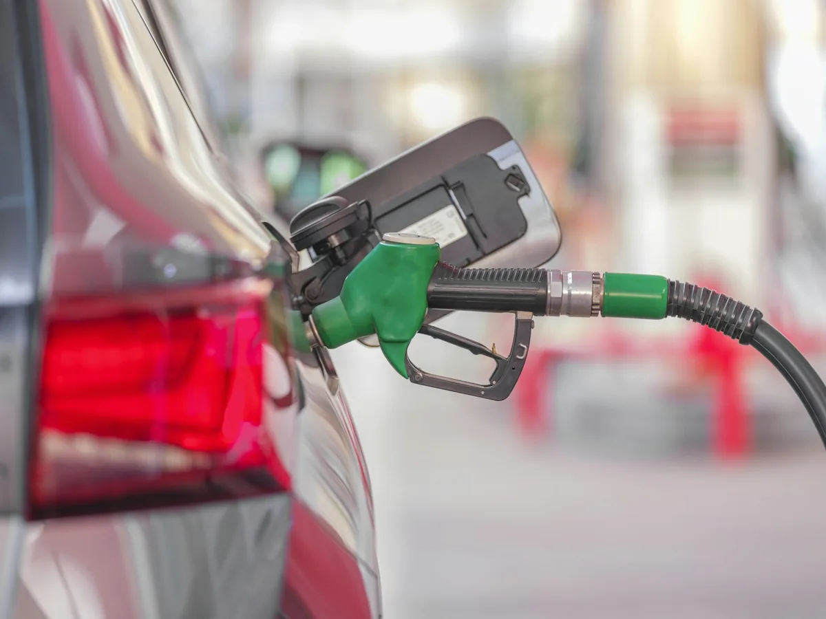 Fuel nozzle in the tank of a red car at a petrol station